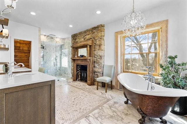 bathroom featuring a stone fireplace, vanity, a chandelier, and independent shower and bath