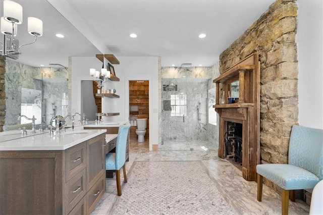 bathroom featuring vanity, a shower with door, toilet, a fireplace, and tile walls