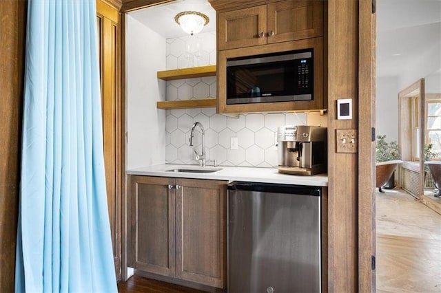 bar with backsplash, sink, stainless steel appliances, and hardwood / wood-style floors