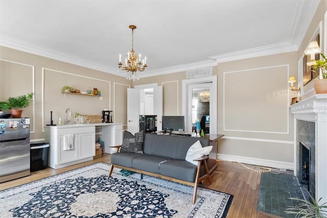 living room with hardwood / wood-style flooring, a notable chandelier, sink, and crown molding