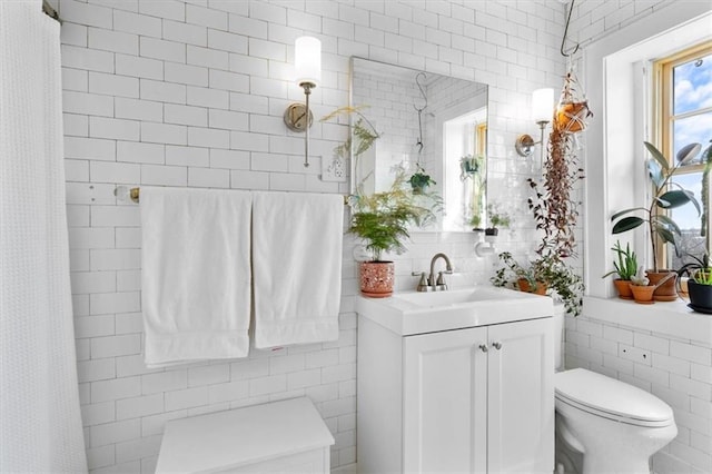 bathroom with a shower with shower curtain, vanity, toilet, and tile walls