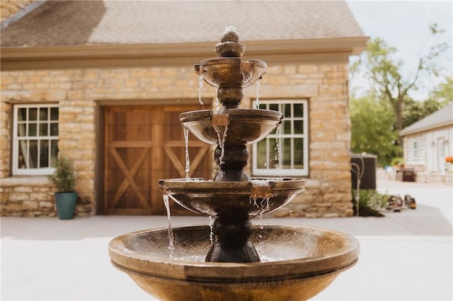 details featuring stone siding, a shingled roof, and central AC unit