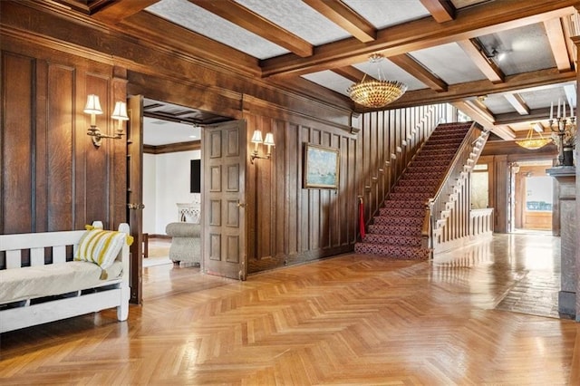 interior space featuring a chandelier, beam ceiling, wood walls, and stairs