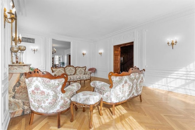 sitting room with ornamental molding, visible vents, and a decorative wall