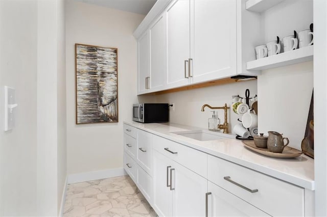 bar with marble finish floor, baseboards, stainless steel microwave, and a sink