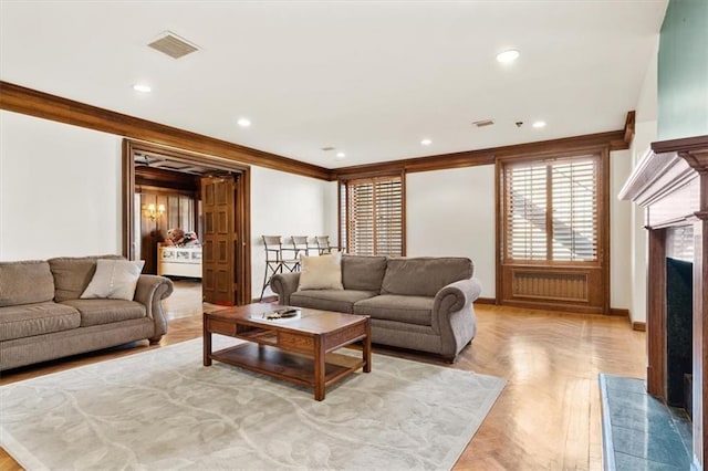 living area with baseboards, visible vents, a high end fireplace, crown molding, and recessed lighting