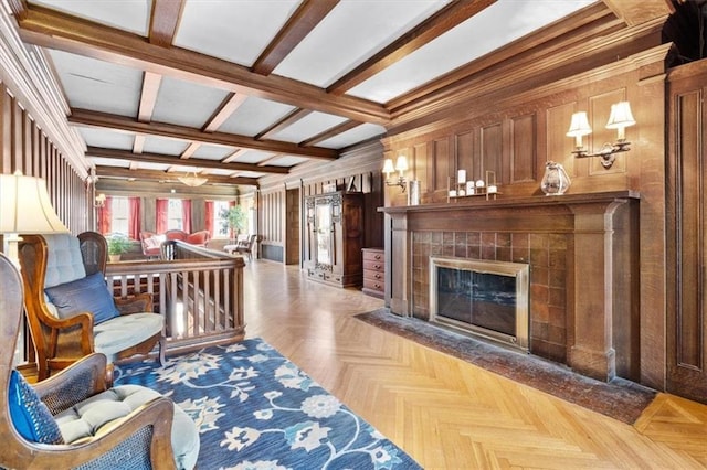 living area featuring wood walls, a tile fireplace, and beam ceiling