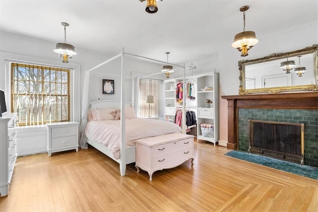 bedroom with light wood finished floors and a fireplace with flush hearth