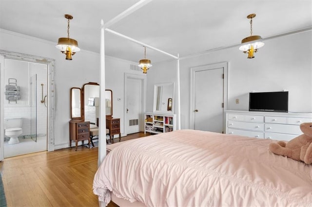 bedroom with ornamental molding, visible vents, connected bathroom, and wood finished floors