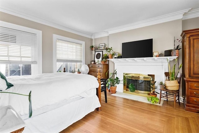 bedroom with ornamental molding, light wood-type flooring, and a fireplace with flush hearth