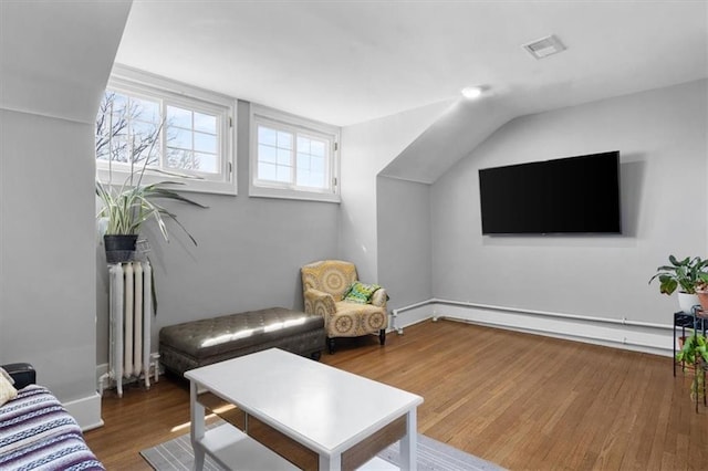 living room with a baseboard heating unit, radiator heating unit, wood finished floors, and visible vents