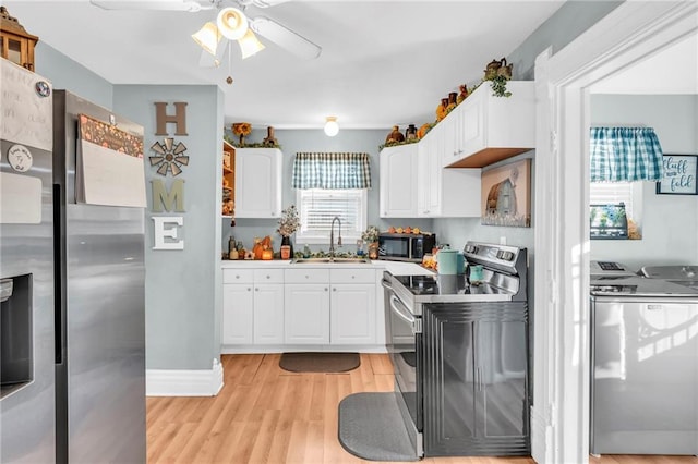 kitchen with appliances with stainless steel finishes, separate washer and dryer, a ceiling fan, and white cabinets
