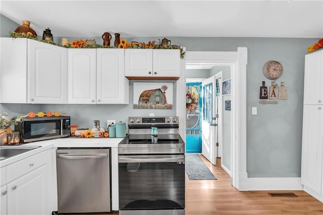 kitchen with appliances with stainless steel finishes, white cabinets, light wood-type flooring, light countertops, and baseboards