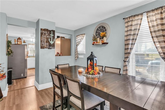 dining area with light wood-type flooring, plenty of natural light, ceiling fan, and baseboards
