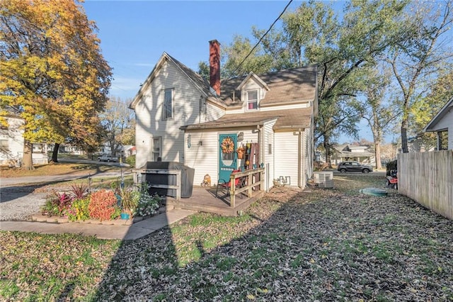 back of house featuring fence, a chimney, central AC unit, and a deck
