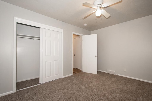 unfurnished bedroom featuring ceiling fan, dark colored carpet, and a closet