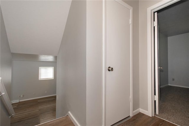 hall featuring vaulted ceiling and dark hardwood / wood-style flooring