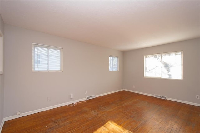 spare room featuring a wealth of natural light and dark hardwood / wood-style flooring