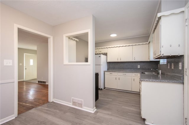 kitchen featuring white cabinetry, white refrigerator, sink, and light hardwood / wood-style floors