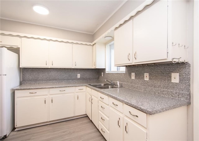 kitchen featuring light hardwood / wood-style floors, sink, ornamental molding, backsplash, and white refrigerator