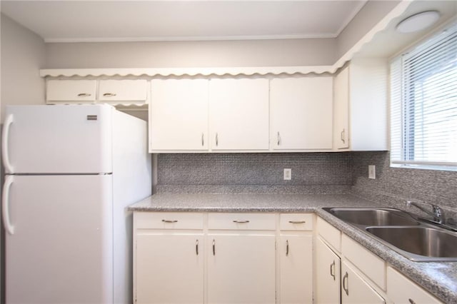 kitchen with decorative backsplash, white cabinetry, white refrigerator, and sink