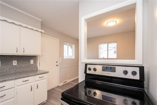 kitchen featuring white cabinetry, black stove, backsplash, and light wood-type flooring