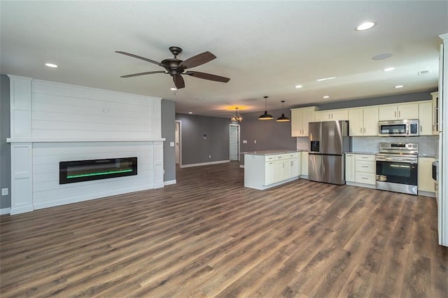 kitchen featuring a large fireplace, pendant lighting, dark hardwood / wood-style floors, and appliances with stainless steel finishes