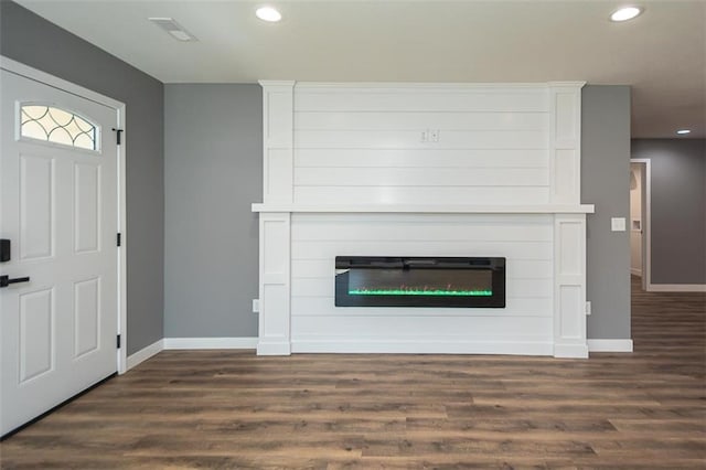 foyer entrance with a large fireplace and dark wood-type flooring