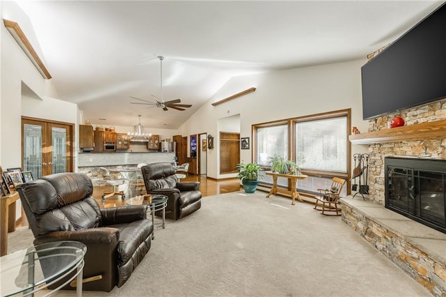 living room featuring light carpet, french doors, vaulted ceiling, ceiling fan, and a fireplace