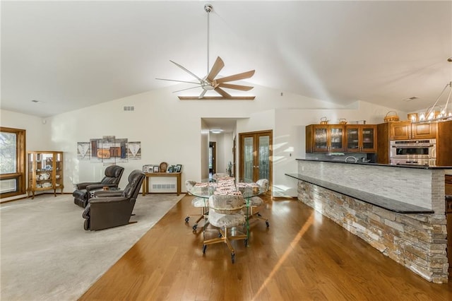 interior space featuring hardwood / wood-style floors, ceiling fan with notable chandelier, and lofted ceiling