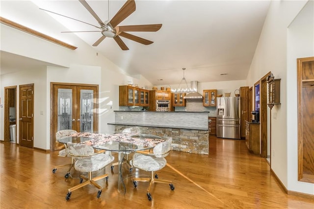 dining room with wood-type flooring, ceiling fan with notable chandelier, and lofted ceiling