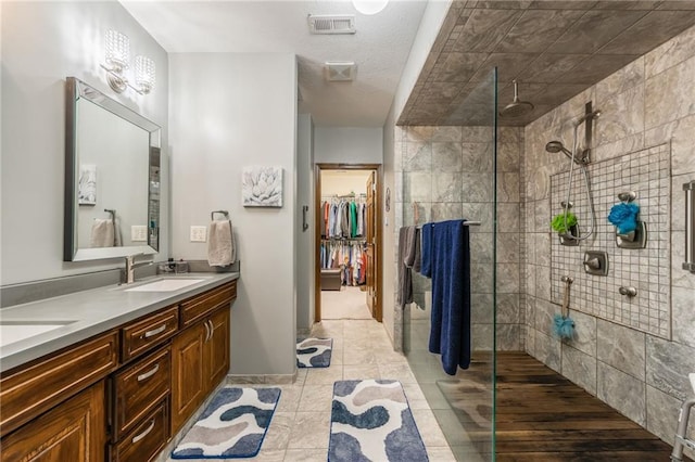 bathroom with a tile shower, vanity, and tile patterned floors