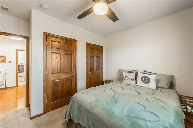 bedroom featuring washer / clothes dryer, ceiling fan, and light colored carpet