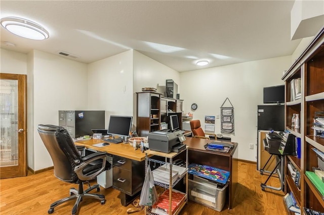 home office with light hardwood / wood-style flooring