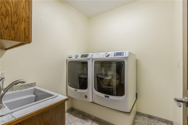 washroom with washing machine and clothes dryer, sink, light tile patterned floors, and cabinets