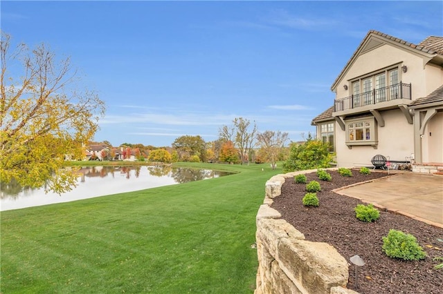 view of yard featuring a water view, a balcony, and a patio area