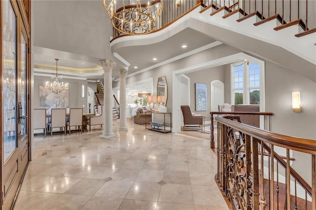 tiled entryway with a high ceiling, decorative columns, and ornamental molding