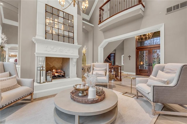 living area featuring french doors, high vaulted ceiling, and an inviting chandelier