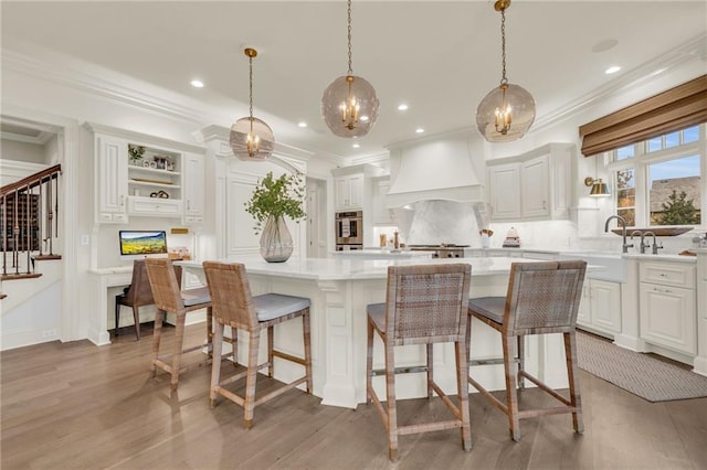 kitchen with white cabinetry, hanging light fixtures, a kitchen island, and stainless steel oven