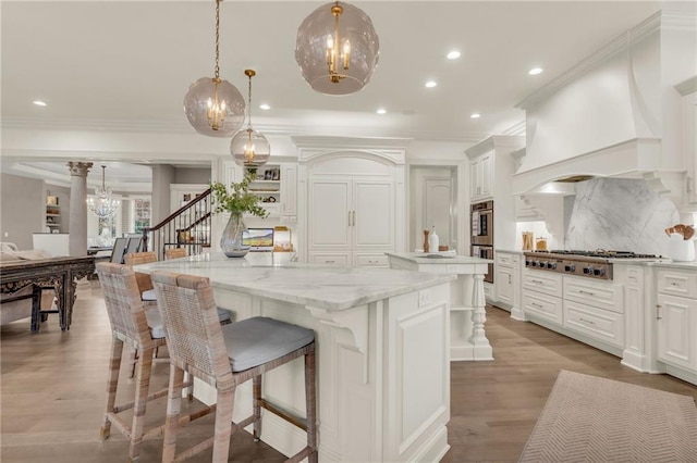 kitchen featuring stainless steel appliances, light stone counters, decorative backsplash, a kitchen island, and decorative light fixtures