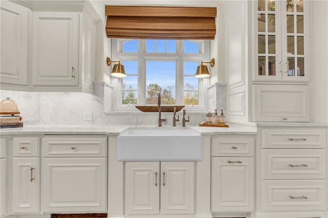 kitchen with white cabinets, sink, and light stone counters