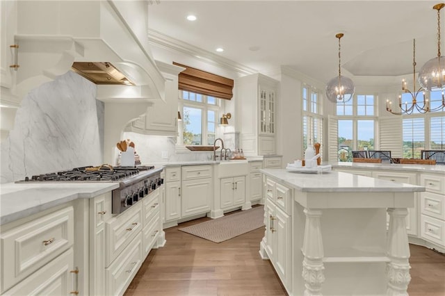 kitchen with tasteful backsplash, a kitchen island, a notable chandelier, light hardwood / wood-style floors, and white cabinets