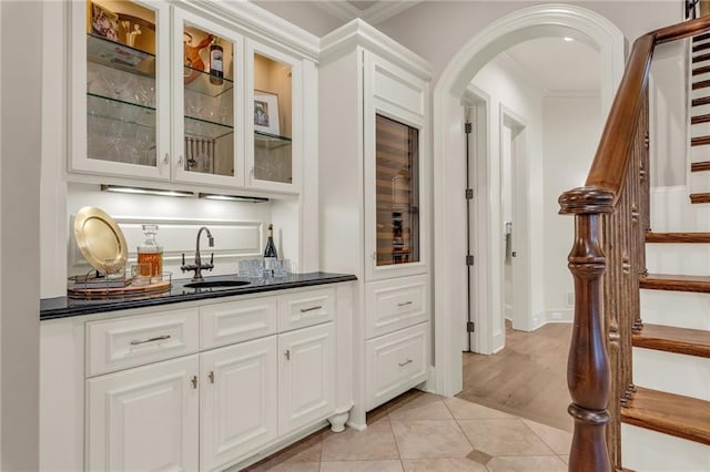 bar with white cabinets, ornamental molding, and sink