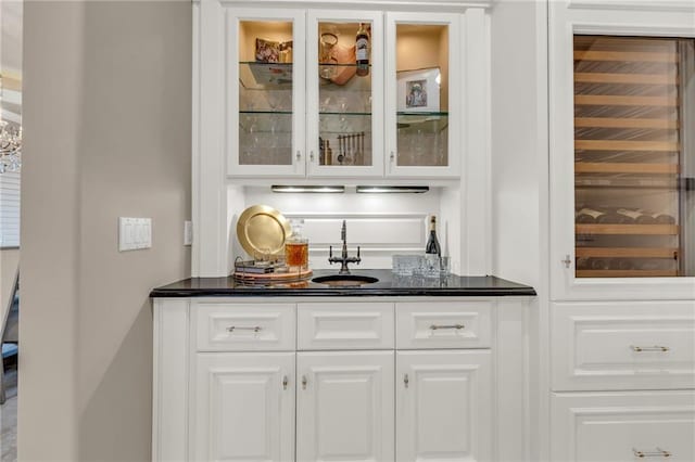 bar with white cabinetry and sink