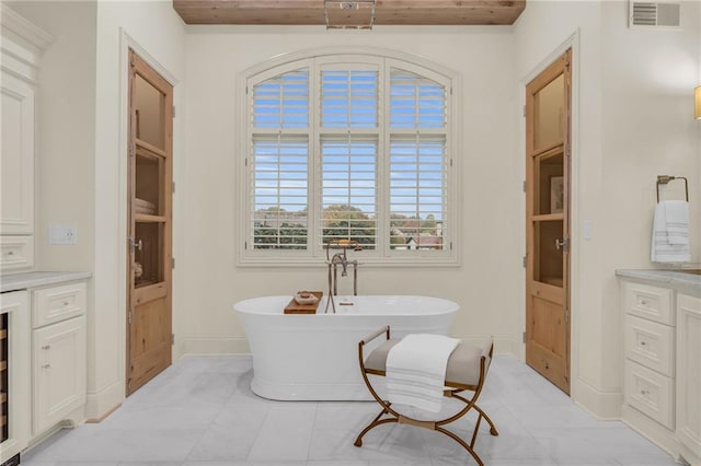 bathroom featuring vanity, a bath, and tile patterned flooring