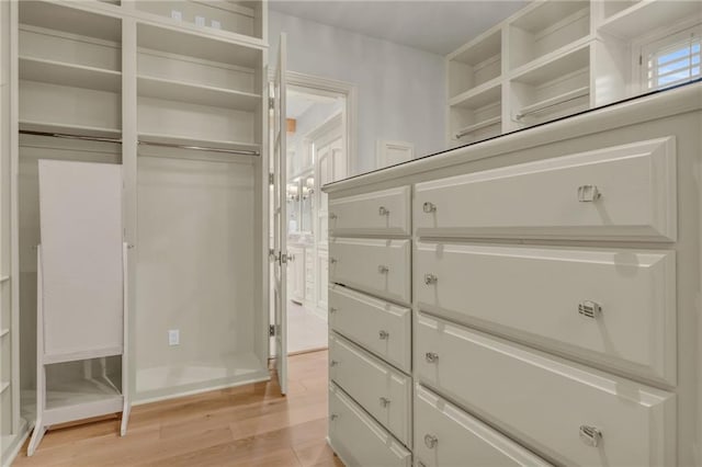 walk in closet with light hardwood / wood-style floors