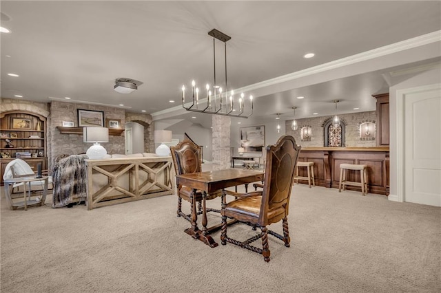 carpeted dining room featuring ornamental molding, bar, and an inviting chandelier