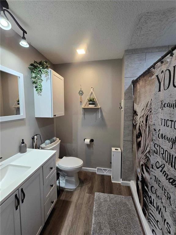 bathroom with hardwood / wood-style flooring, a shower with curtain, a textured ceiling, vanity, and toilet