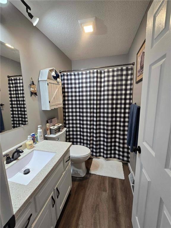 bathroom with hardwood / wood-style floors, vanity, a textured ceiling, and toilet