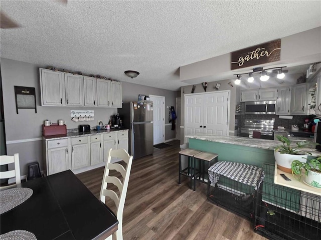 kitchen featuring white cabinets, a textured ceiling, tasteful backsplash, dark hardwood / wood-style floors, and appliances with stainless steel finishes